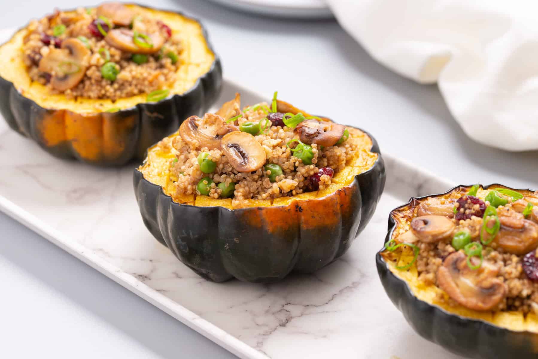 A close up view of three stuffed acorn squash placed in a serving plate.