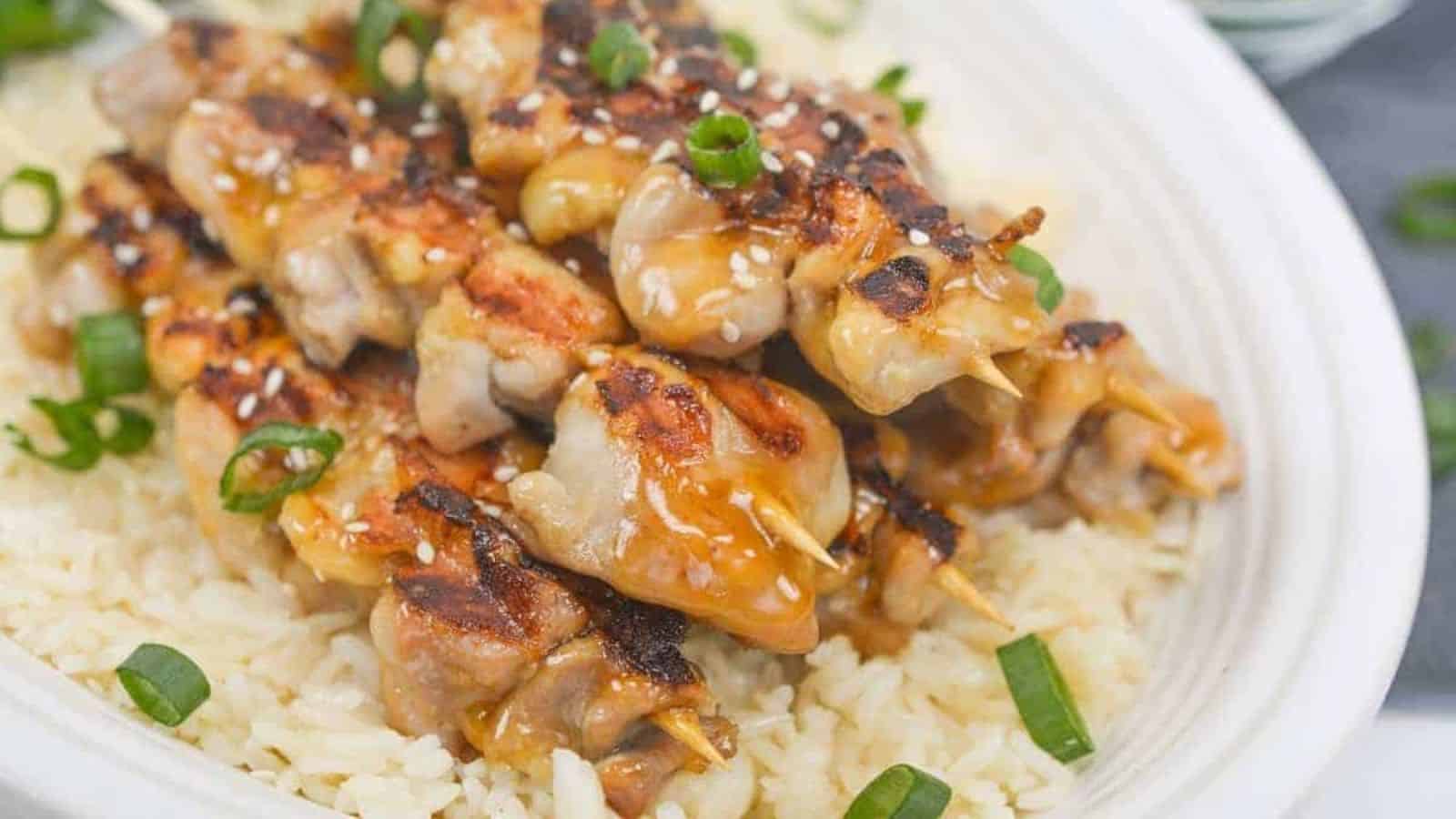 Asian chicken skewers on top of rice.