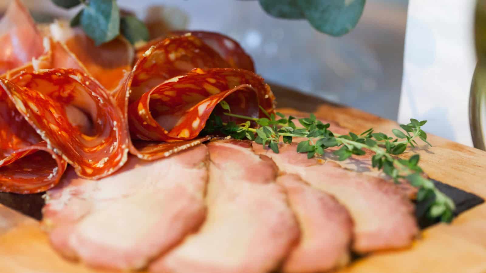 Close-up of ham slices in a wooden board.