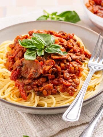 An image of bolognese in a bowl with basil on top.