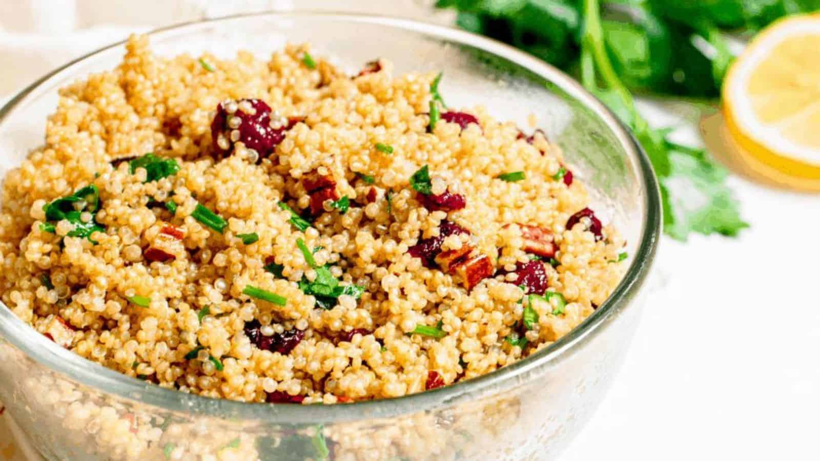 A glass bowl filled with quinoa, dried cranberries, and pecans.