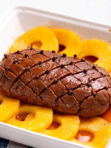 Overhead photo of vegan ham with pineapple slices placed on a white serving dish.