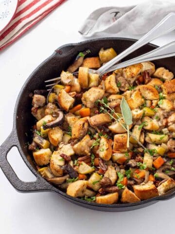 An overhead view of skillet with stuffing and a fork and spoon in it.