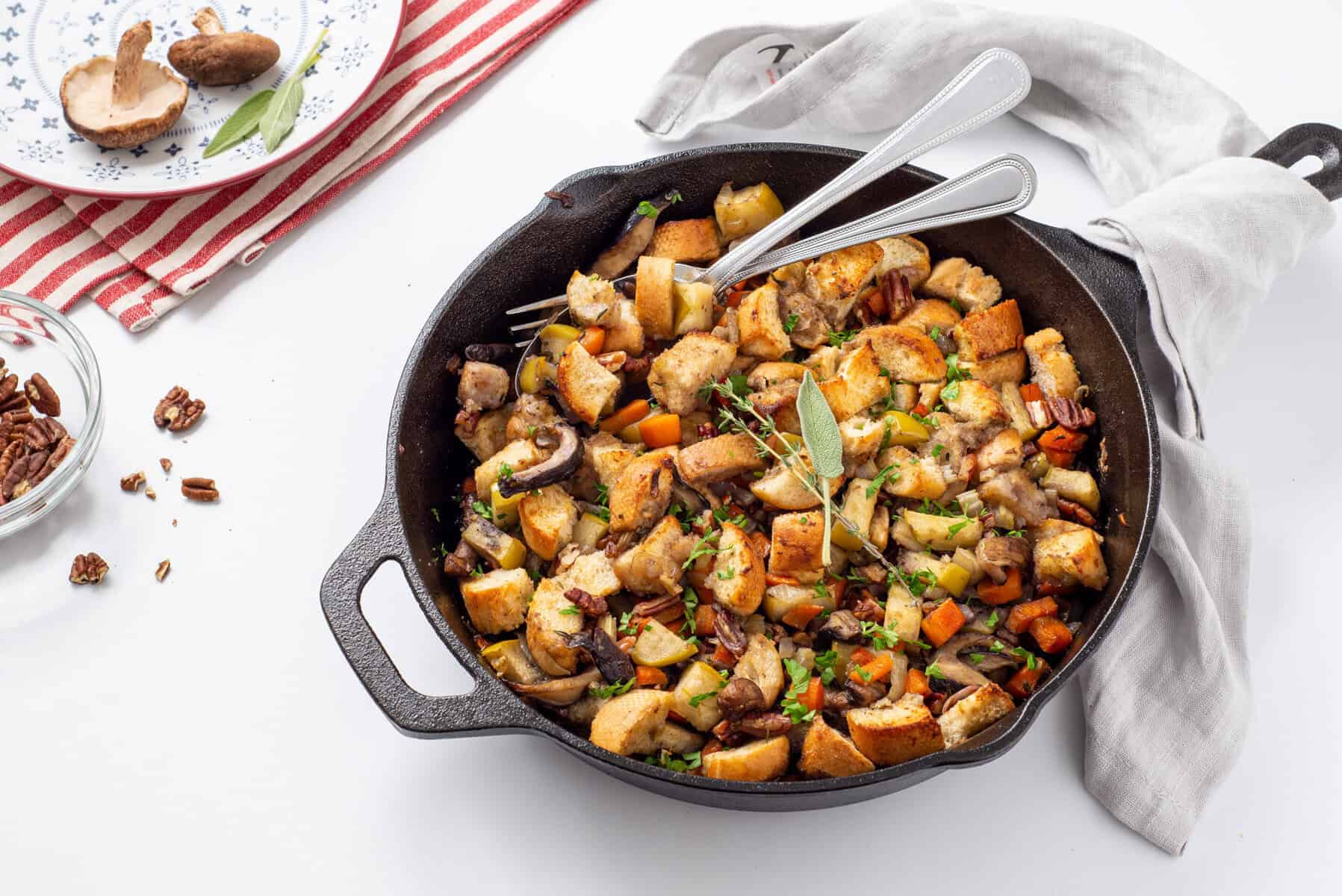 An overhead view of skillet with stuffing and a fork and spoon in it.