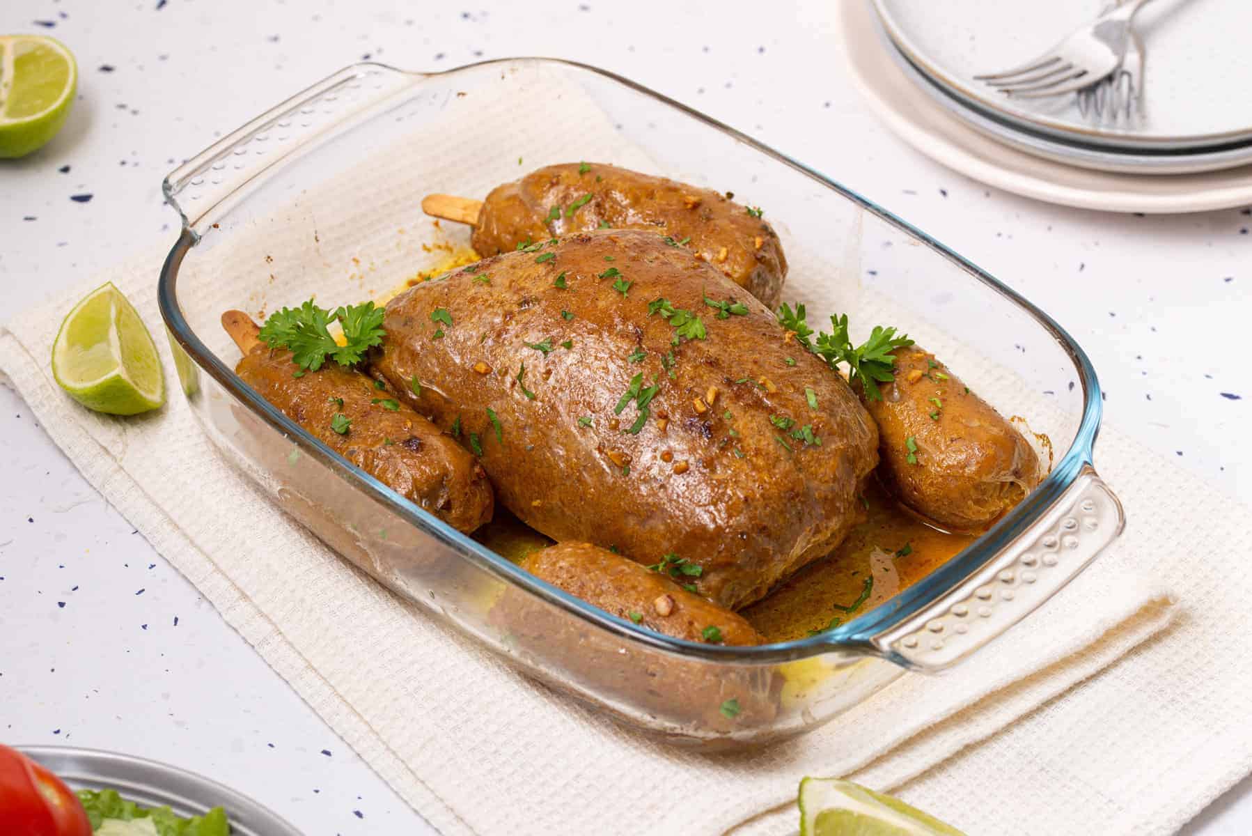 Vegan Turkey Roast in a glass baking dish on a countertop, garnished with herbs.