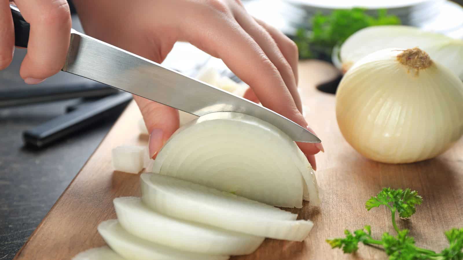 Woman cutting white onion.