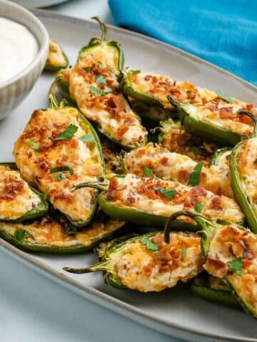 Jalapeño Poppers on a platter with a bowl of dipping sauce.