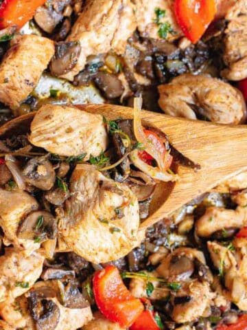 Garlic chicken bites with peppers and mushrooms in a skillet.