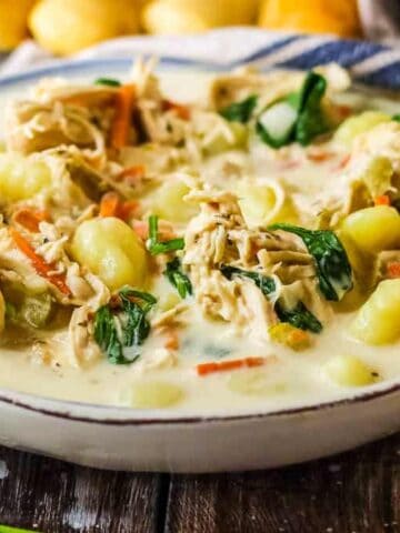 Bowl of copycat Olive Garden chicken gnocchi soup in a bowl with breadsticks in the background.
