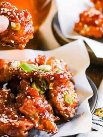 Low angle shot of korean fried chicken with a hand holding a piece of the chicken.