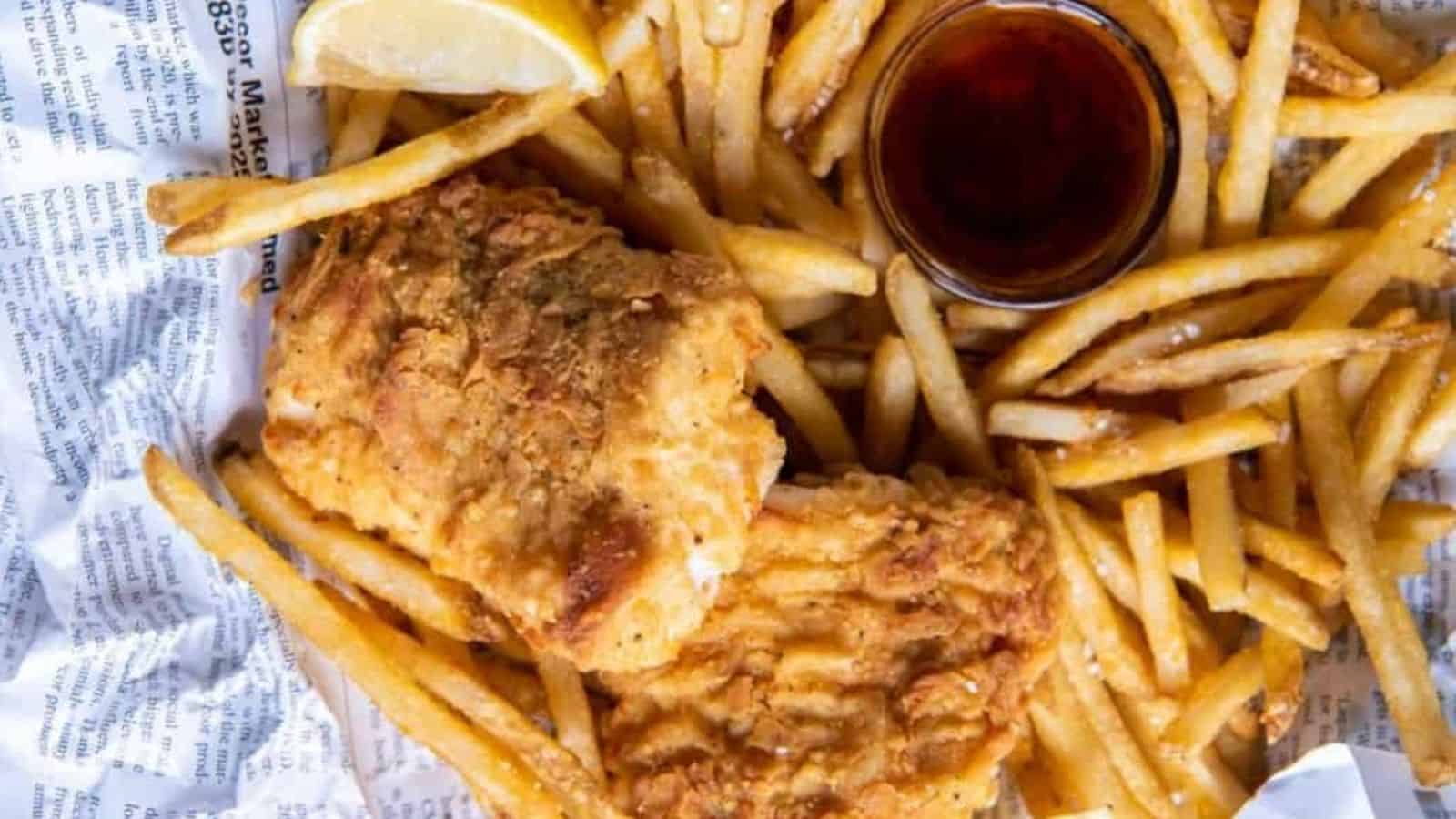 Overhead image of air fryer fish and chips with a dip on a newspaper.