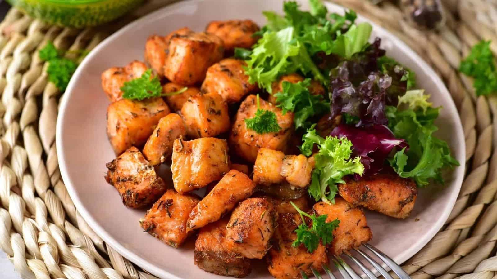 Air Fryer Salmon Bites and a salad on a plate with a fork.