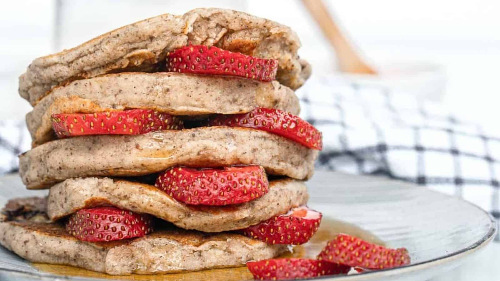 A stack of pancakes with strawberries on top.