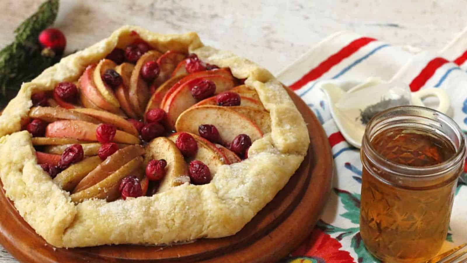 Apple cranberry galette on a wood board with a cup of tea.