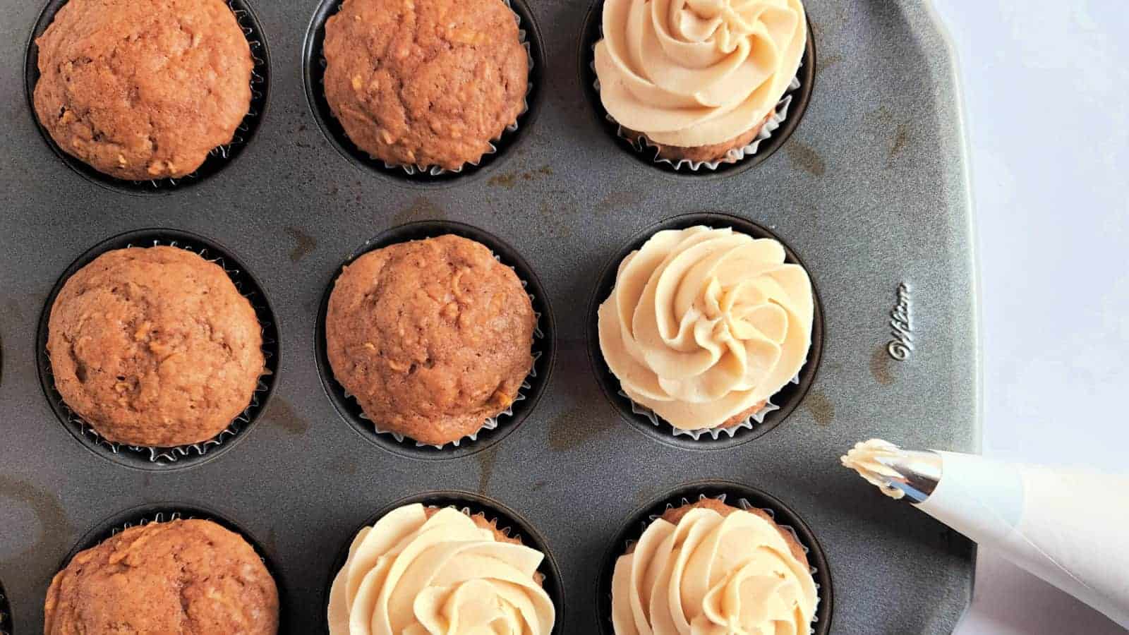 Frosted and unfrosted apple cupcakes in a muffin tin.