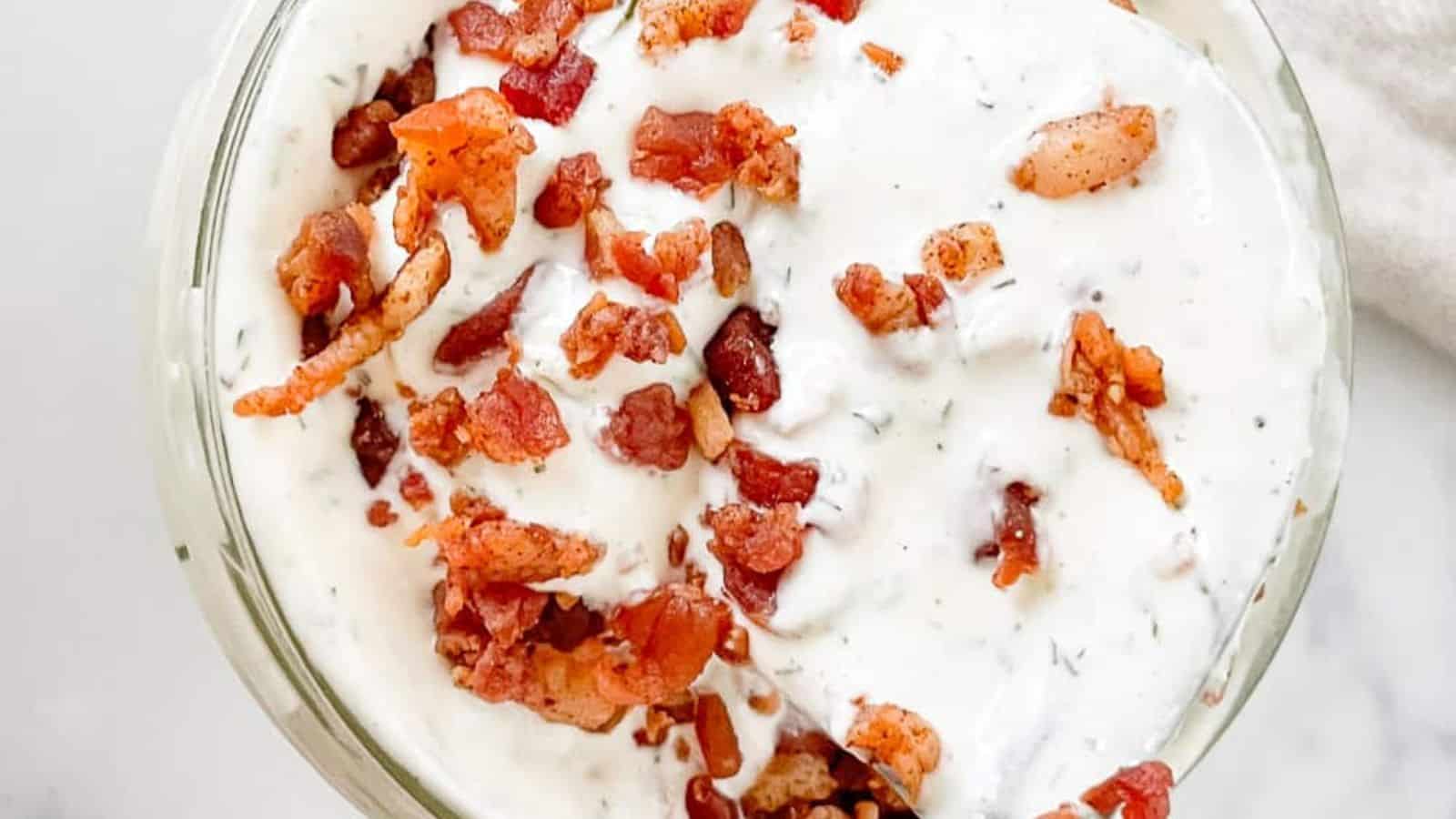 Overhead view of bacon ranch dressing topped with bacon bits in a glass.