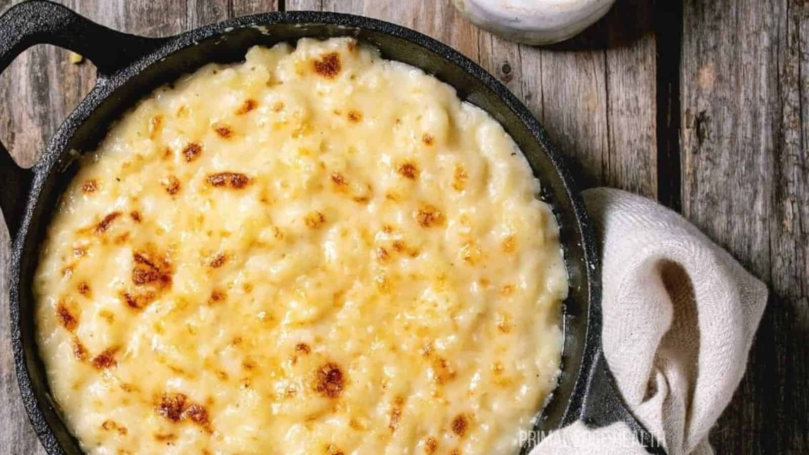 A picture of baked cauliflower mac and cheese in cast iron skillet on wooden table.