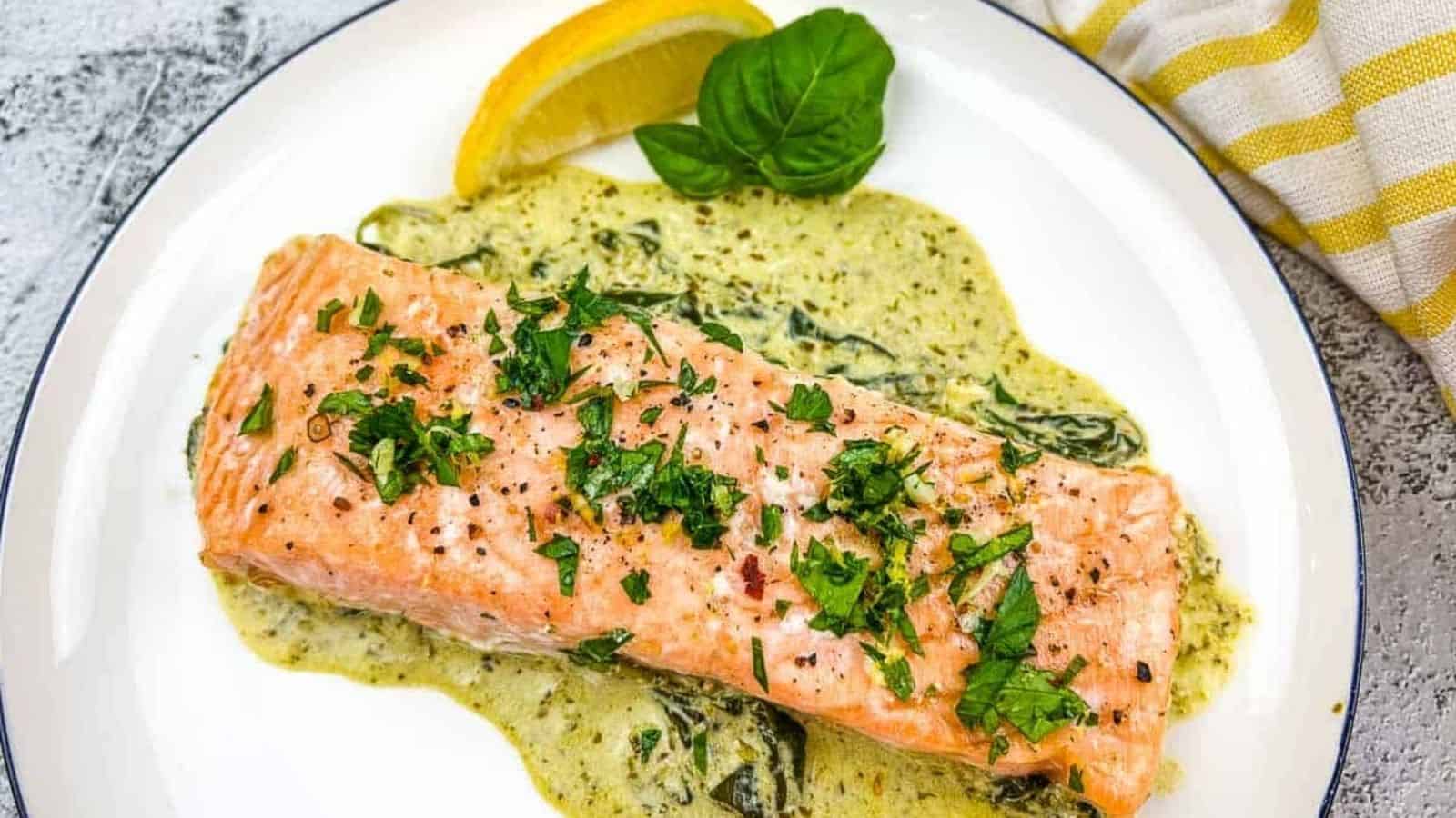 Salmon with spinach sauce on a white plate.