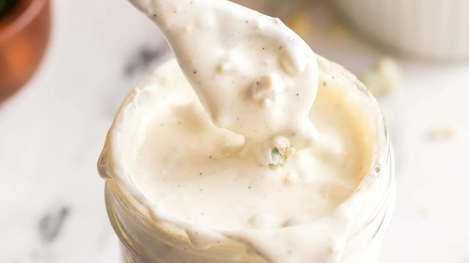 Close-up of a spoonful of blue cheese dressing from a glass.