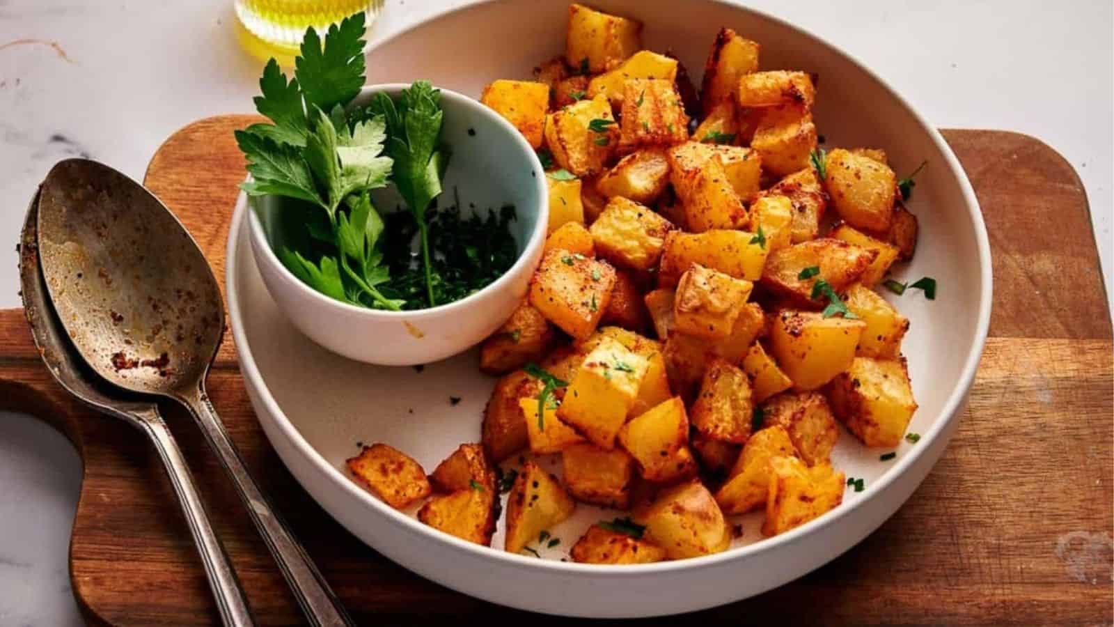 Breakfast potatoes with parsley on a wooden cutting board.