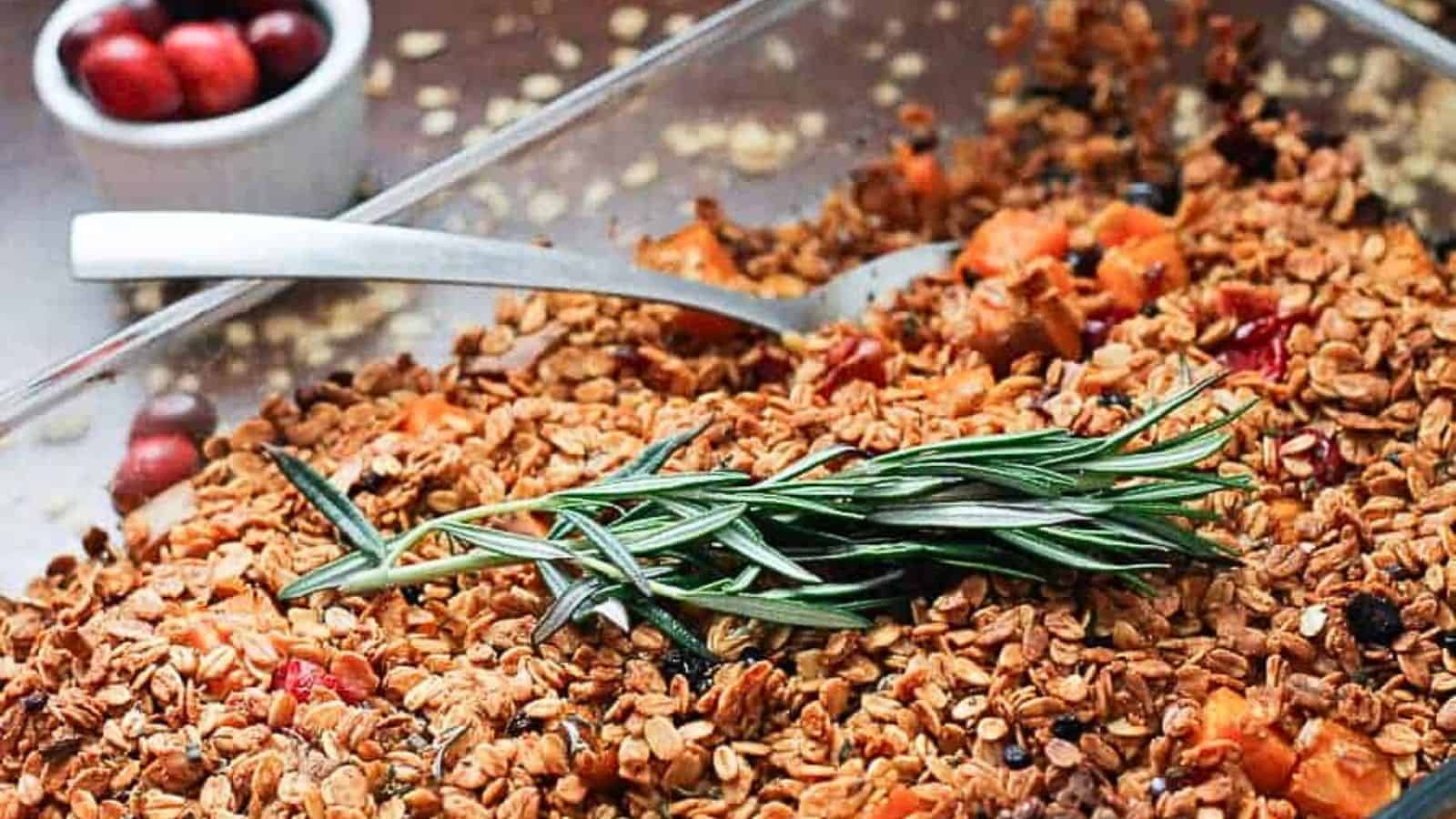 A dish of granola with cranberries and sprigs of rosemary.