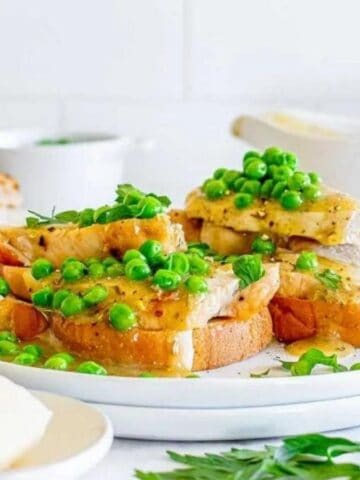 Front view image of canadian hot turkey sandwich in a white plate garnished with green peas.