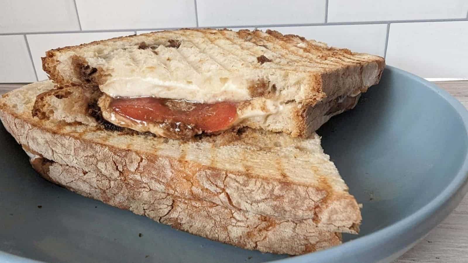 Image shows a sliced caprese panini on a wooden board with the melted cheese oozing out.