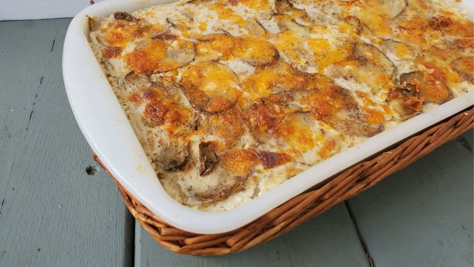 Cheesy scalloped potatoes in a casserole dish on a blue wooden table.