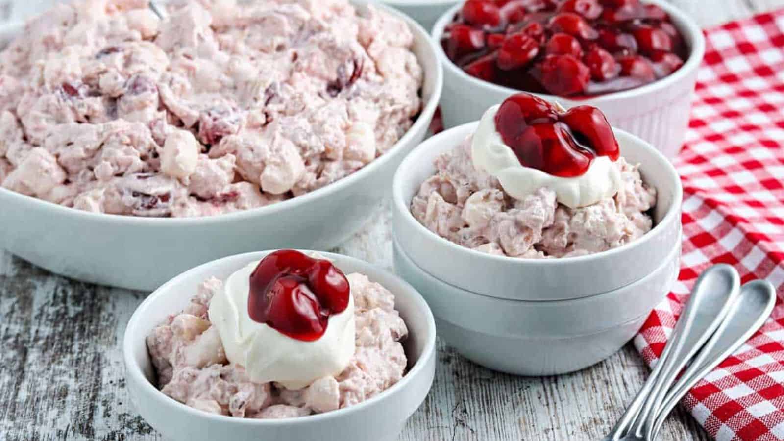 Cherry fluff salad in blue bowls with whipped cream.