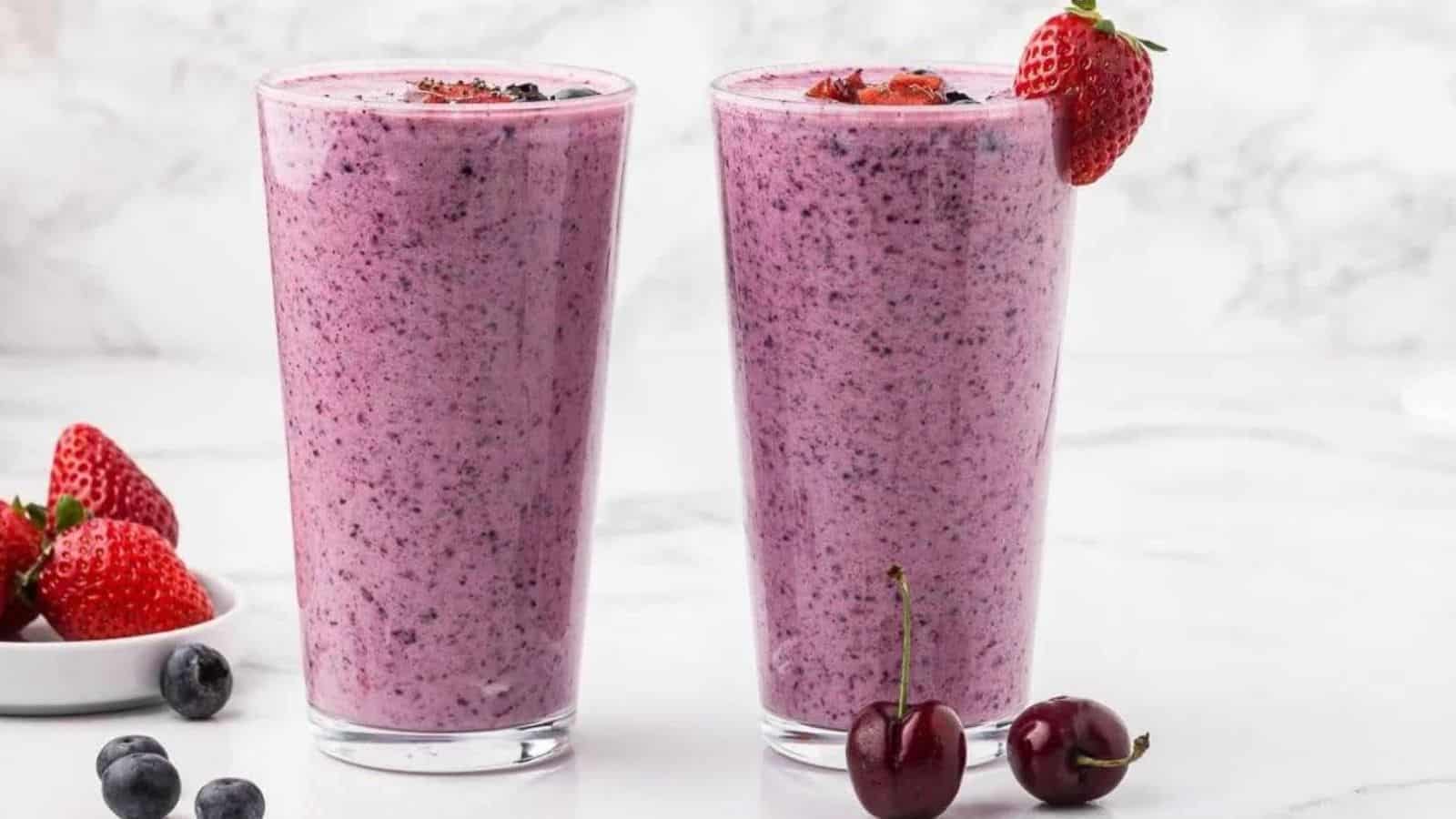 Two tall glasses filled with berry smoothie with chia seeds.