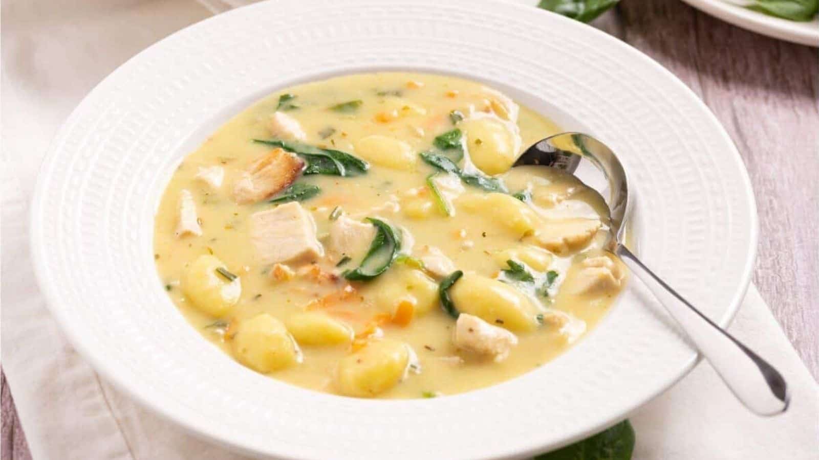 A bowl of chicken and spinach soup with a spoon.