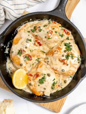 Creamy chicken in a cast iron skillet with capers.
