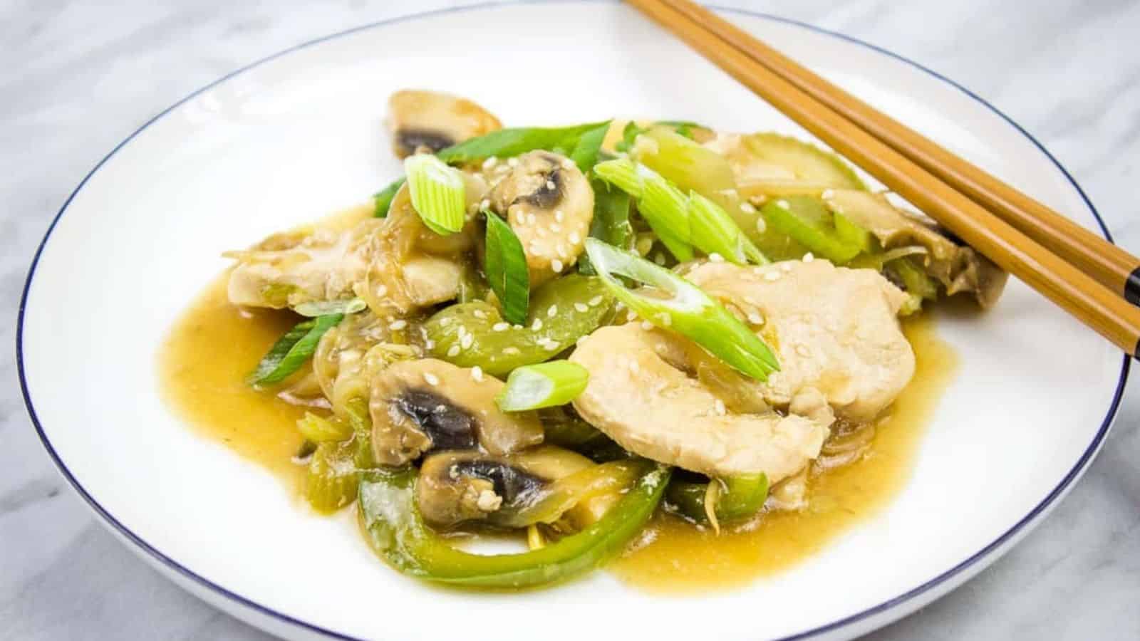 A white plate with chicken and mushrooms in a sauce.