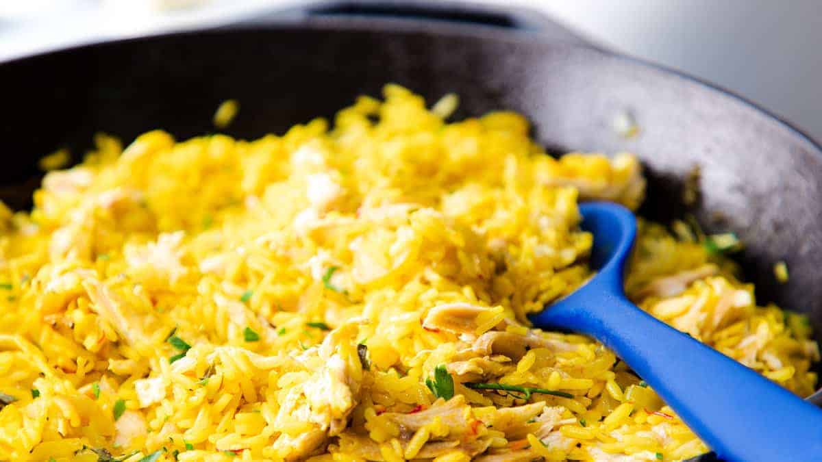 Chicken and yellow rice in a black skillet.