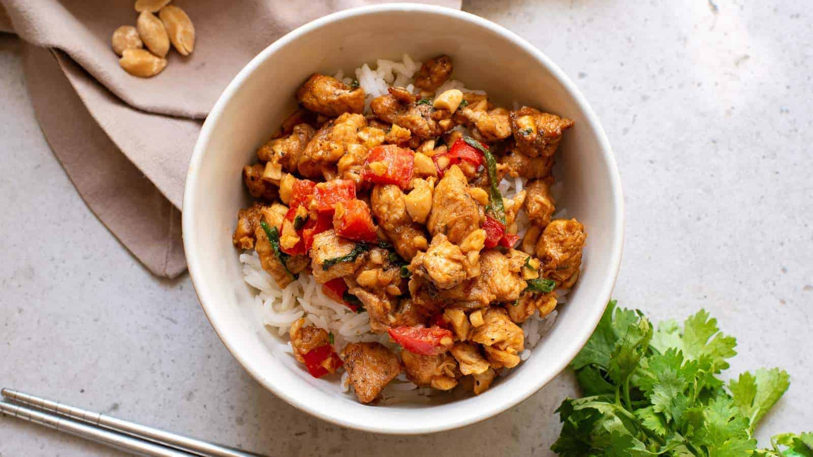 Chicken stir fry in a white bowl with chopsticks.