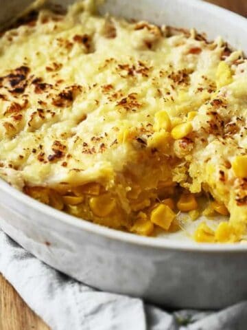 Corn casserole in a casserole dish with a portion removed.