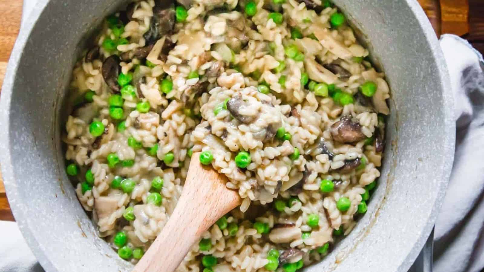 Mushroom risotto with peas and mushrooms in a pot with wooden spoon.