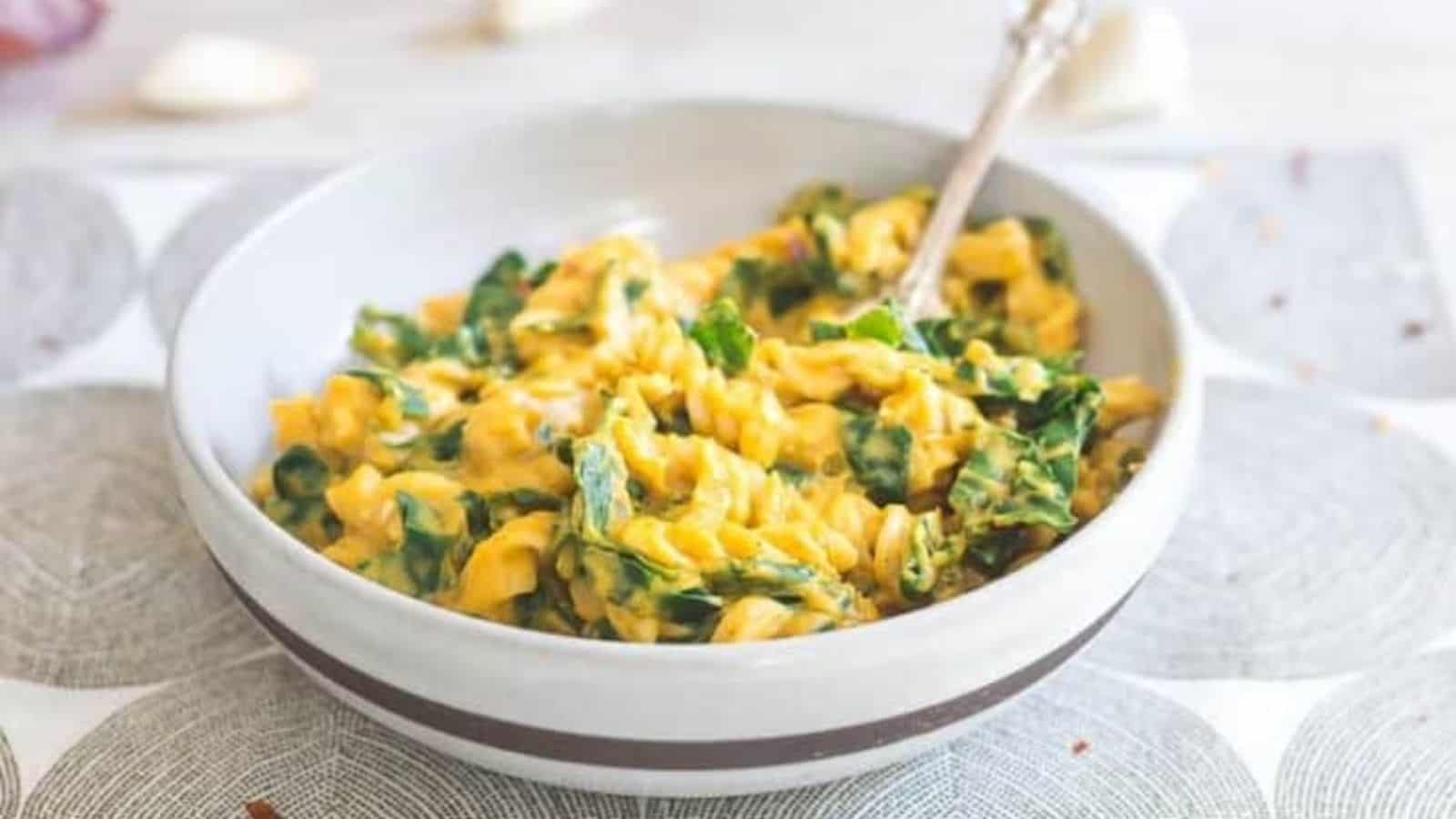 Close-up of creamy pumpkin garlic pasta with tuscan kale in a bowl.