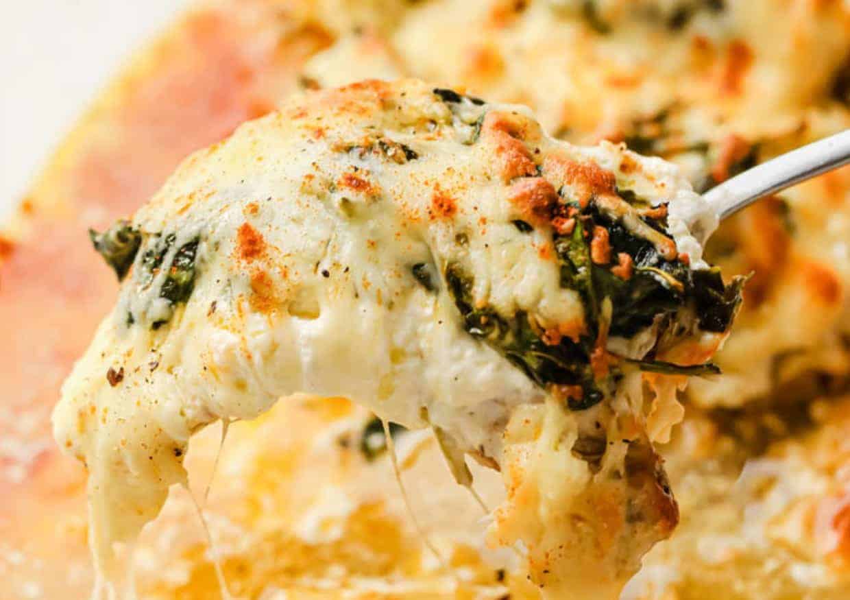 A serving spoon serving of creamy spinach chicken bake.