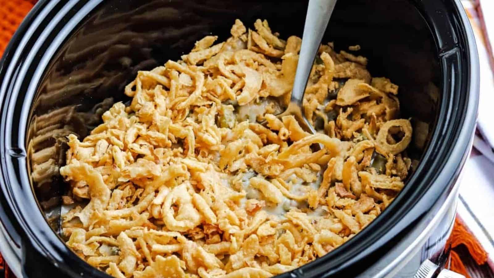 Slow cooker with green bean casserole topped with fried onions.