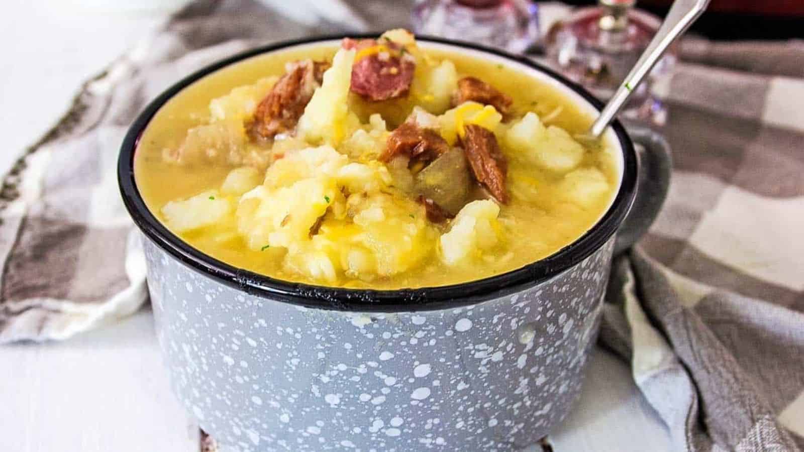 Ham and Potato soup in a gray and white bowl with a spoon.