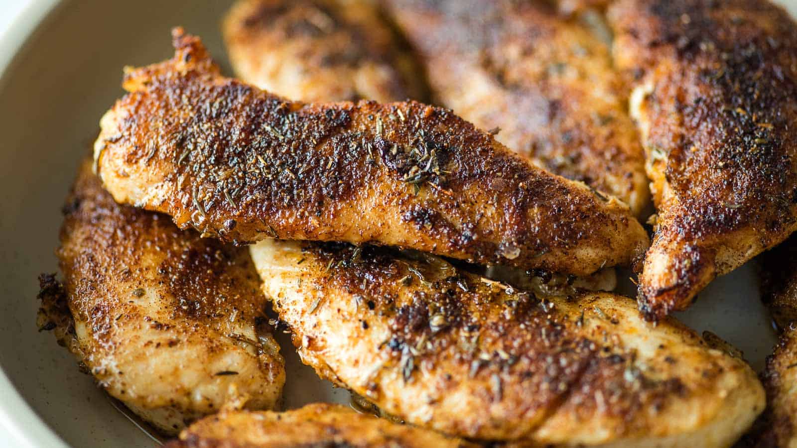 Blackened chicken tenders in a white dish.