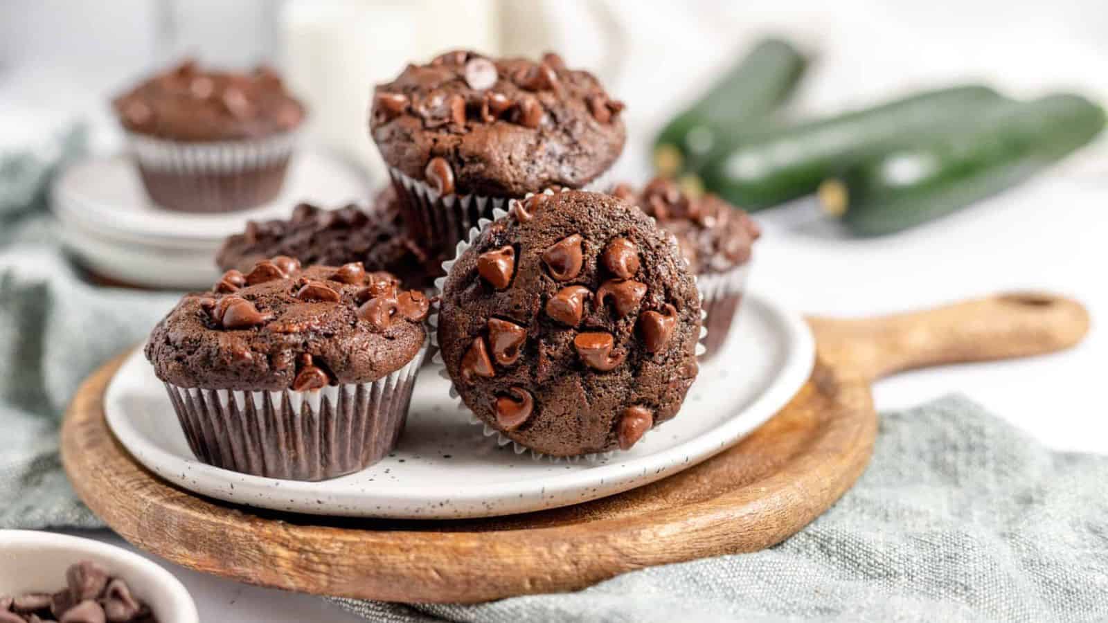 A plate of double chocolate zucchini muffins on a wooden board.