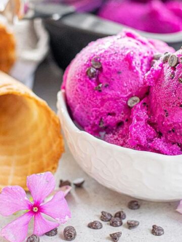 A bowl of dragon fruit ice cream with some cones.