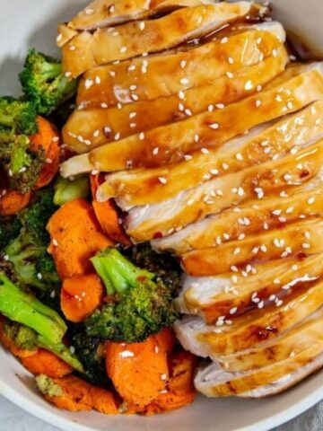 Easy Air Fryer Teriyaki Chicken Breast in a white bowl with sesame seeds, carrots, and broccoli.