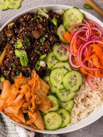 Top view of beef bulgogi with various vegetables and rice in a bowl.