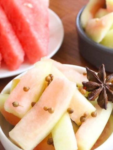 A small bowl with watermelon rind pickles and star anise on top.