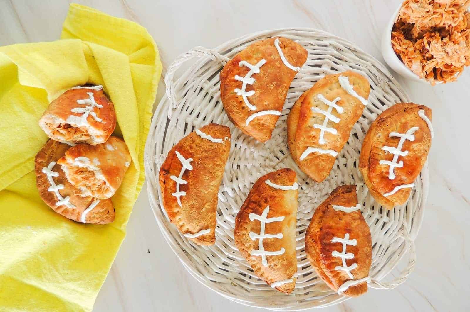 A basket of football shaped buffalo chicken pockets on a table.