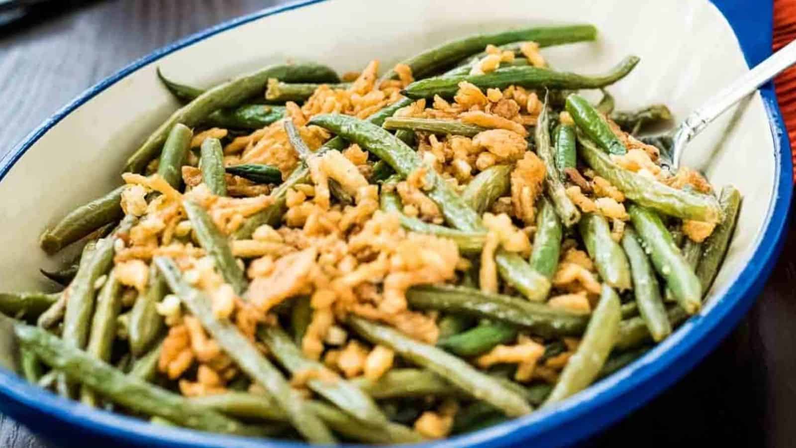 Close-up image of garlicky green beans with fried onions in a plate.