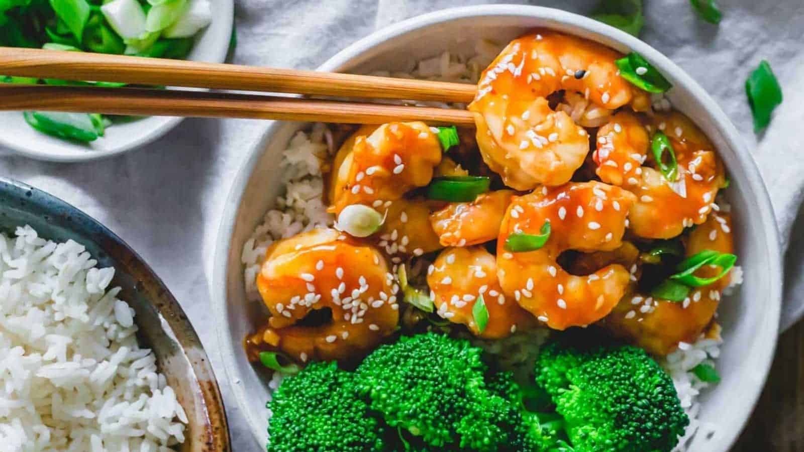 Homemade general tso shrimp with broccoli and rice in a bowl with chopsticks.